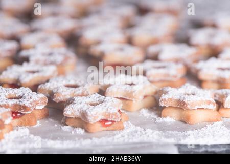 Ein Backblech voller sternförmiger Shortbread-Kekse mit Marmelade und Puderzucker-Weihnachtsplätzchen Stockfoto