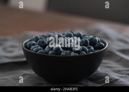 Große Schüssel mit Heidelbeeren auf dem Tisch, flacher Fokus Stockfoto