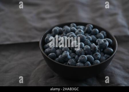 Große Schüssel mit Heidelbeeren auf dem Tisch, flacher Fokus Stockfoto