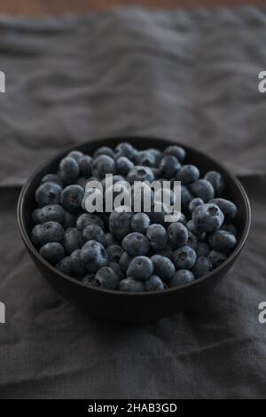 Große Schüssel mit Heidelbeeren auf dem Tisch, flacher Fokus Stockfoto