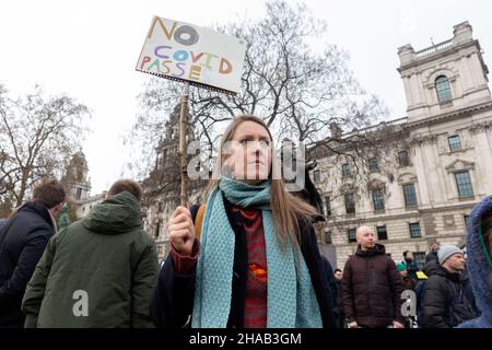 London, Großbritannien. 11th Dez 2021. Ein Protestierender sah während der Demonstration ein Schild mit der Aufschrift "Keine COVID-Pässe" an.gemeinsam unter der Leitung von Big Brother Watch und Migrant Organize, Demonstranten versammelten sich, um Unzufriedenheit über den Versuch der britischen Regierung zu äußern, Impfpass und andere Formen von COVID-Ausweisen zu einer Voraussetzung für Großveranstaltungen und den Eintritt in öffentliche Räume zu machen. Die Gruppe versucht, den Unterschied zwischen Anti-Impfstoff-Pässen speziell und Anti-Impfstoffen, mit denen sie sich mit dem Ersteren identifizieren, klar zu definieren. Kredit: SOPA Images Limited/Alamy Live Nachrichten Stockfoto