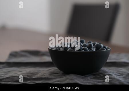 Große Schüssel mit Heidelbeeren auf dem Tisch, flacher Fokus Stockfoto