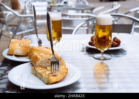 Eiskalte Biere, die auf der Terrasse in Gläser gegossen werden, mit Tapas, spanischem Omelett und Chicken Wings. Platz für Kopie Stockfoto