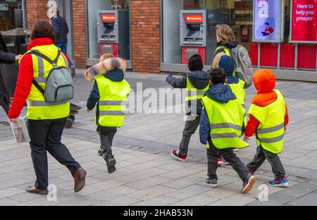 Schutz von Schulkindern mit fluoreszierenden Warnjacken auf einem Spaziergang durch Southport mit Lehrern, Merseyside, Großbritannien Stockfoto