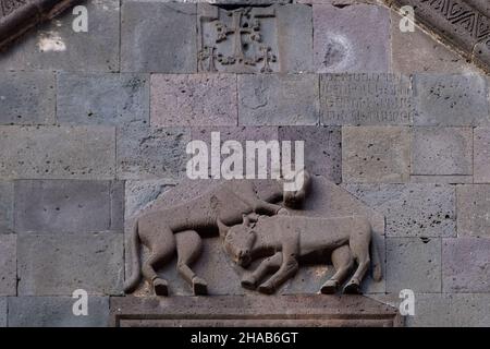 Schnitzwerk, das einen Löwen zeigt, der einen Ochsen an der Südfassade der Katoghike-Kapelle im mittelalterlichen Kloster Geghard angreift, das im 4th. Jahrhundert von Gregor dem Erleuchter in der armenischen Provinz Kotayk gegründet wurde Stockfoto