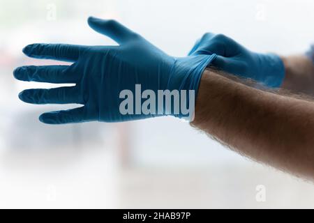 Nahaufnahme Mann mit blauen sterilen medizinischen Schutzhandschuhen Stockfoto