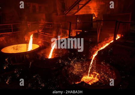 Ein Strahl aus geschmolzenem Stahl wird in Schöpfkellen gegossen. Metallurgische Industrie Stockfoto