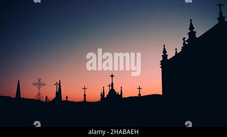 Silhouetten von Kreuzen in einem Friedhof in der Dämmerung. Stockfoto