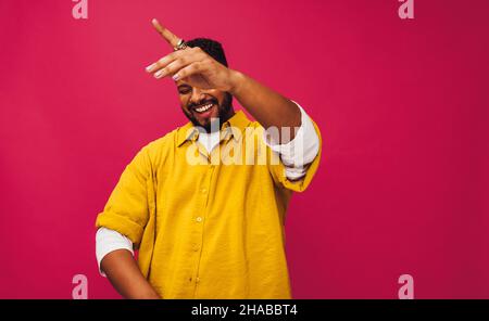 Junger Mann, der in einem Studio zu Musik tanzt. Fröhlicher junger Mann, der fröhlich lächelt, während er seiner Lieblingsmusik lauscht. Hübscher junger Mann, der alleine steht Stockfoto