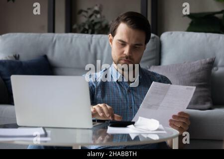 Mann hält Rechnungen, Quittungen, mit Rechner berechnet Summe zu zahlen Stockfoto