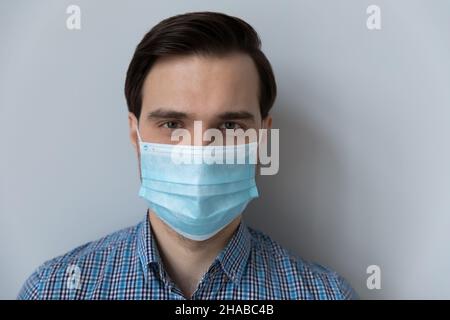 Mann trägt eine Gesichtsmaske, die die Kamera in Innenräumen betrachtet Stockfoto