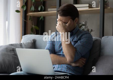 Verärgert Mann sitzen auf dem Sofa mit Laptop Stockfoto