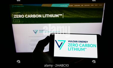 Person, die das Smartphone mit dem Logo des australischen Unternehmens Vulcan Energy Resources Ltd auf dem Bildschirm vor der Website hält. Konzentrieren Sie sich auf die Telefonanzeige. Stockfoto
