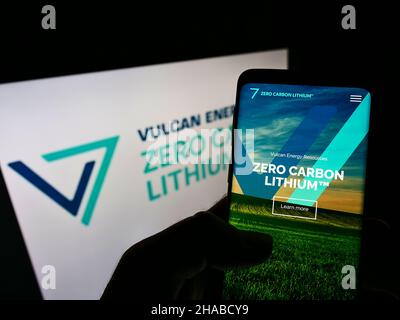 Person mit Mobiltelefon auf der Website des australischen Unternehmens Vulcan Energy Resources Ltd. Auf dem Bildschirm mit Logo. Konzentrieren Sie sich auf die Mitte des Telefondisplays. Stockfoto