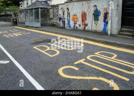 Eine Bushaltestelle mit einem Wandgemälde, auf dem die Menschen vor Ort, die auf einen Bus warten, Builth Wells, Powys, Wales, abgebildet sind Stockfoto