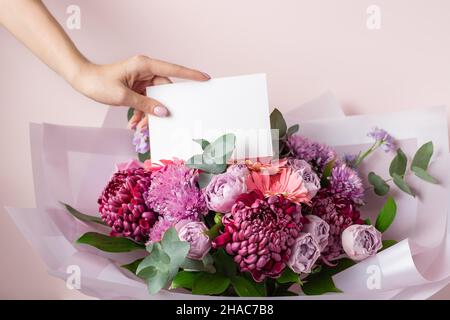Blumenhändler Hand Lege leere Papierkarte auf schönen Blumenstrauß Stockfoto