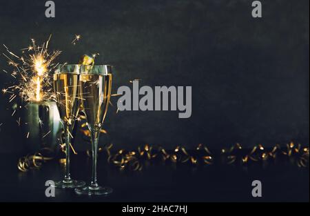 Zwei Gläser Champagner mit Glitzerleuchten auf schwarzem Hintergrund Stockfoto