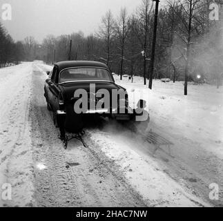 Polska, 1970. Dzieci na sankach przyczepionych do samochodu Wo³ga GAZ-21 na zaœnie¿onej drodze. ³p PAP/Edmund Uchymiak Dok³adny miesi¹c i dzieñ wydarzenia nieustalone. Polen, 1970. Kinder auf einem Schlitten an Wolga GAZ-21 Auto auf einer verschneiten Straße befestigt. ³p PAP/Edmund Uchymiak Stockfoto