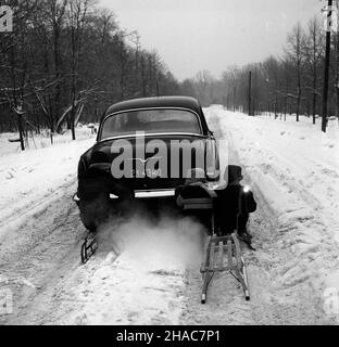 Polska, 1970. Dzieci na sankach przyczepionych do samochodu Wo³ga GAZ-21 na zaœnie¿onej drodze. ³p PAP/Edmund Uchymiak Dok³adny miesi¹c i dzieñ wydarzenia nieustalone. Polen, 1970. Kinder auf einem Schlitten, der am Wolga GAZ-21 Auto auf einer schneebedeckten Straße befestigt ist. lp PAP/Edmund Uchymiak Stockfoto