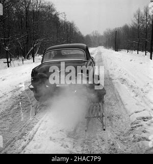 Polska, 1970. Dzieci na sankach przyczepionych do samochodu Wo³ga GAZ-21 na zaœnie¿onej drodze. ³p PAP/Edmund Uchymiak Dok³adny miesi¹c i dzieñ wydarzenia nieustalone. Polen, 1970. Kinder auf einem Schlitten, der am Wolga GAZ-21 Auto auf einer schneebedeckten Straße befestigt ist. lp PAP/Edmund Uchymiak Stockfoto