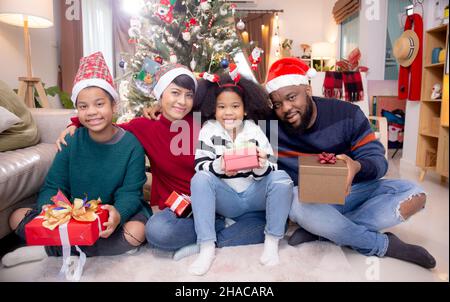 Glückliche Familie Vater und Mutter und Tochter sitzen und mit Geschenk-Box zu Hause, Feier in Weihnachten mit überraschenden und Freude zu Hause, danke Stockfoto