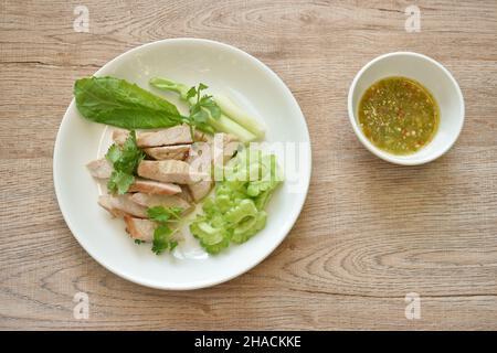 Gebratenes Schweinefleischsoße-Dressing mit Limettenknoblauchsoße und Salat mit Chilisauce auf dem Teller Stockfoto