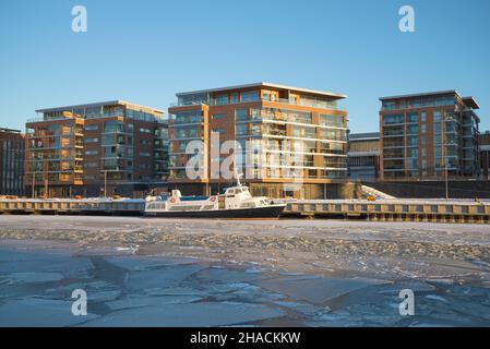 TURKU, FINNLAND - 23. FEBRUAR 2018: Moderne Mehrfamilienhäuser am Ufer des Aurajoki Flusses an einem sonnigen Februarabend Stockfoto