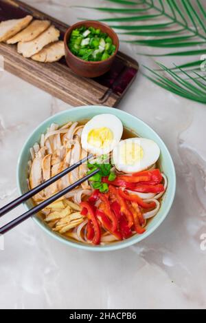 Heiße leckere japanische Nudelsuppe Ramen mit Hühnergemüse, grünen Zwiebeln und Ei mit Essstäbchen Stockfoto