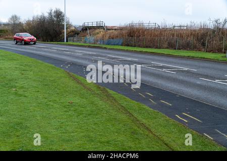 Newhame Rd, Montrose, Angus, Schottland, 12th vom 2021. Dezember: Bild: Die Nachwirkungen eines ernsthaften RTC, bei dem eine Hündin getötet wurde, als ein Auto die Kontrolle über die scharfe Kurve der Newhame Rd verlor, den Straßenbelag aufbog, die Hündin-Geherin schlug und dann in den Bahndamm stürzte. Der tödliche RTC ereignete sich um 8,20pm Uhr am Samstag, dem 11th. Dezember 2021. Gelbe Markierungen auf der Straße stammen von der Polizei und veranschaulichen den Weg, den das Auto eingeschlagen hat. Mitglieder der Öffentlichkeit wurden gesehen, um Blumen in einem Zeichen des Respekts für die Frau zu legen, die starb.Quelle:Barry Nixon/Alamy Live News Stockfoto