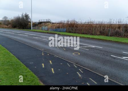 Newhame Rd, Montrose, Angus, Schottland, 12th vom 2021. Dezember: Bild: Die Nachwirkungen eines ernsthaften RTC, bei dem eine Hündin getötet wurde, als ein Auto die Kontrolle über die scharfe Kurve der Newhame Rd verlor, den Straßenbelag aufbog, die Hündin-Geherin schlug und dann in den Bahndamm stürzte. Der tödliche RTC ereignete sich um 8,20pm Uhr am Samstag, dem 11th. Dezember 2021. Gelbe Markierungen auf der Straße stammen von der Polizei und veranschaulichen den Weg, den das Auto eingeschlagen hat. Mitglieder der Öffentlichkeit wurden gesehen, um Blumen in einem Zeichen des Respekts für die Frau zu legen, die starb.Quelle:Barry Nixon/Alamy Live News Stockfoto