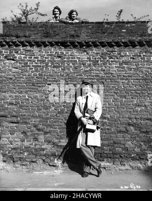 JAMES STEWART am Drehort offen an einer Wand in einer Landstraße am Stadtrand von West Drayton London mit zwei Frauen, die während der Dreharbeiten von NO HIGHWAY IN THE SKY auf ihn herabblicken 1951 Regisseur HENRY KOSTER Roman Nevil Shute UK-USA Koproduktion Twentieth Century Fox Stockfoto