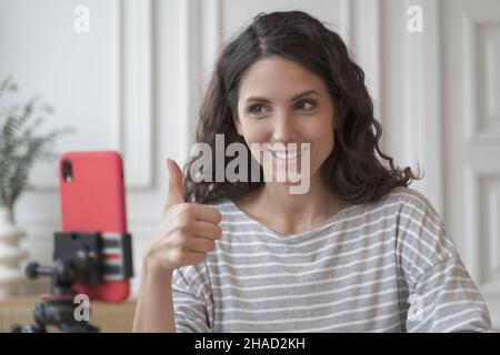Positive fröhliche italienische Frau Blogger Aufnahme Video für Blog auf dem Smartphone, zeigt Daumen nach oben Stockfoto