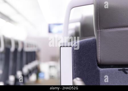 Eine leere Kabine des aeroexpress-Zuges ohne Passagiere. Weiche Sitze in einer Reihe mit Kopfstützen aus Leder. Öffentlicher Ort. Selektiver Fokus. Nahaufnahme Stockfoto