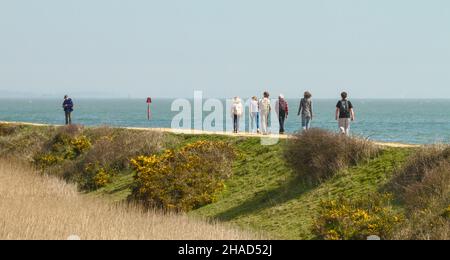 Menschen, die auf der Meeresmauer zwischen Lymington und Keyhaven, Solent Way Fußweg Großbritannien, spazieren gehen
