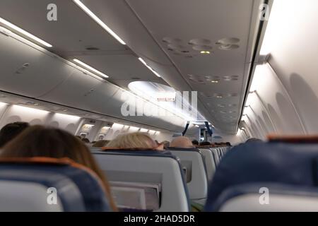 Die Kabine des Flugzeugs mit Passagieren auf ihren Sitzen vor dem Start. Öffentlicher Ort. Selektiver Fokus. Nahaufnahme Stockfoto