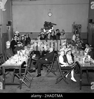 1965, historisch, Gruppe von Kindern und einigen Erwachsenen auf einer Dorfweihnachtsfeier, Longwick Village Hall, Buckinghamshire, England, Großbritannien. Speisen und Getränke werden auf traditionellen tresseltischen aus Holz serviert. Stockfoto