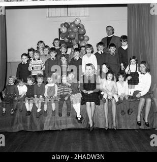 1965, historisch, Gruppe von Kindern, unterschiedlichen Alters, sitzen zusammen auf der Bühne in Longwick Village Hall, Buckiinghamshire, Großbritannien nach der Weihnachtsfeier. Stockfoto