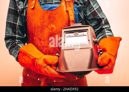 Schweißer im Schutzanzug, Handschuhe, mit Schweißmaske, Nahaufnahme, Feurige Farben Stockfoto