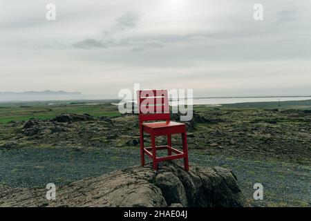 Roter Holzstuhl in Island mit einer malerischen Landschaft auf dem Babckground. Hochwertige Fotos Stockfoto