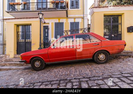 Ein altes rotes Auto, das auf der gepflasterten Straße geparkt wurde Stockfoto