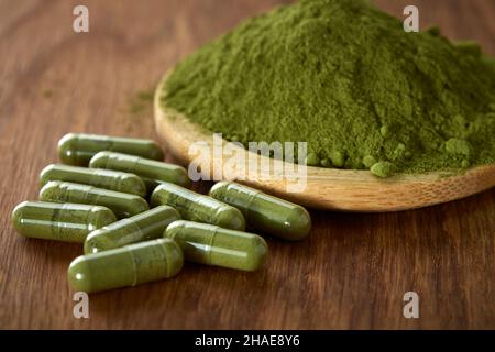 Kapseln gefüllt mit Moringa Pulver auf Holzhintergrund - Nahaufnahme Stockfoto