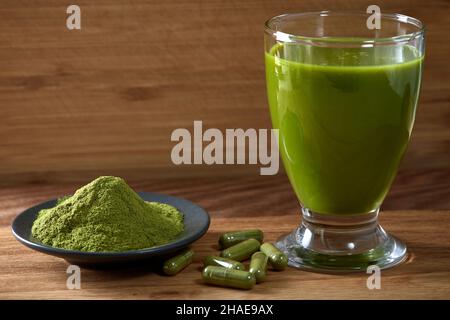 Kapseln gefüllt mit Moringa-Pulver und Moringa-Saft auf Holzboden Stockfoto