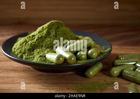 Kapseln gefüllt mit Moringa Pulver auf Holzhintergrund - Nahaufnahme Stockfoto