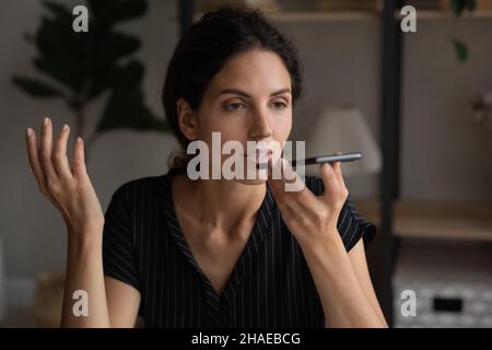 Hispanische Frau zeichnet Sprachnachrichten auf dem Smartphone auf Stockfoto
