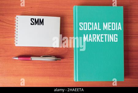 SMM Text - MARKETING IN SOZIALEN NETZWERKEN auf einem Bürotisch mit einem Stift und Notizblock. Stockfoto