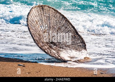 schilfschirm am Strand in der Brandung, vom Wind während eines Sturms weggeblasen Stockfoto