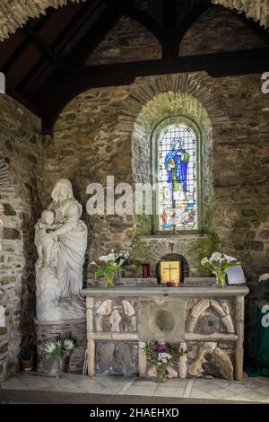 Kapelle der Muttergottes und des Hl. Non, Pembrokeshire, Wales, Großbritannien, mit einer Marmorstatue der Siegesmutter und einem Buntglasfenster, das den Hl. Non darstellt Stockfoto