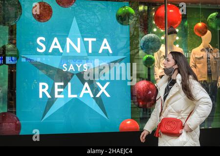 Oxford Street London, Großbritannien, 12th. Dezember 2021. Die Menschen betrachten bunte Fensterdekorationen und Botschaften auf John Lewis. Käufer und Besucher in London drängen sich heute in die geschäftige Oxford Street, obwohl die Infektionsraten mit der neuen Omnicron-covid-Variante in London und im weiteren Land schnell ansteigen und die Regierung die Einführung weiterer Maßnahmen erwägt, um den Trend einzudämmen. Stockfoto