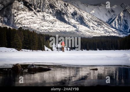 Ein Hockeyspieler, der eine Pause auf einem gefrorenen Bergsee in Banff, Alberta, Kanada, hat Stockfoto