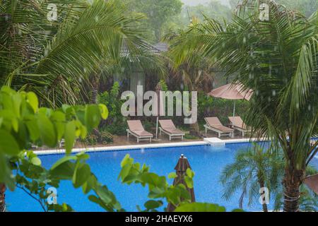 Tropischer Sommerregen fällt großer Regen fällt auf das Schwimmbad in der Nähe des Meeres am Strand auf der Insel Phu Quoc, Vietnam, Südostasien. Konzept o Stockfoto